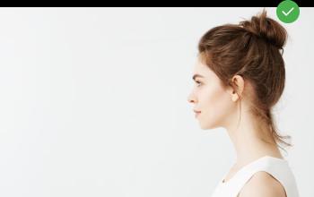 Woman standing in profile half a metre from a light wall